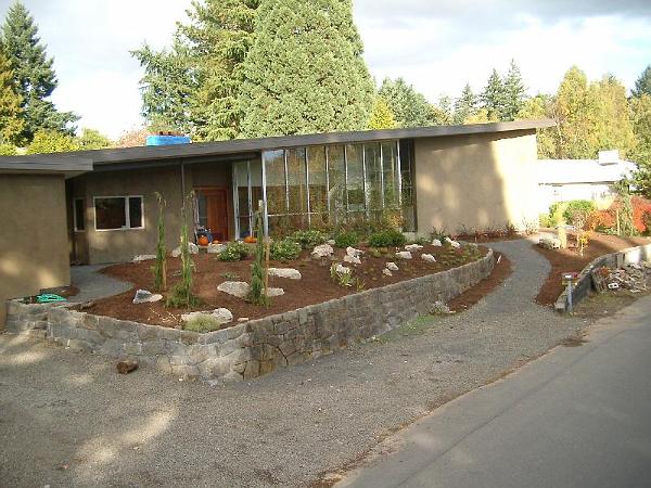 IMGP2369.JPG - Rocks, conifers, heather, and japanese maples added to the front.  Vines (silvervein creeper) climbing the trellis to shade the sun room.